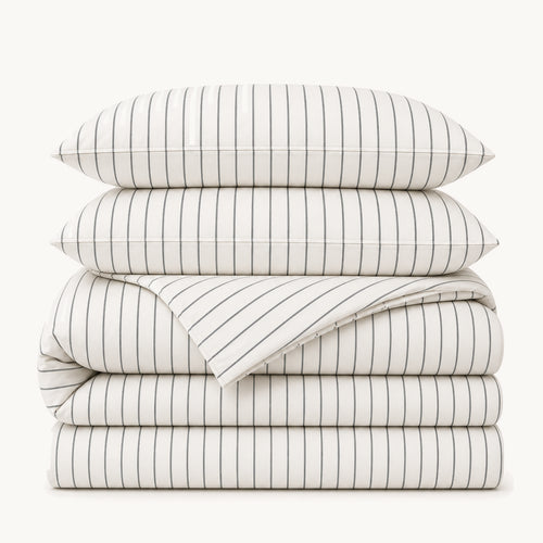 Stacked White Stripe cotton sateen bedding set on a warm off-white background